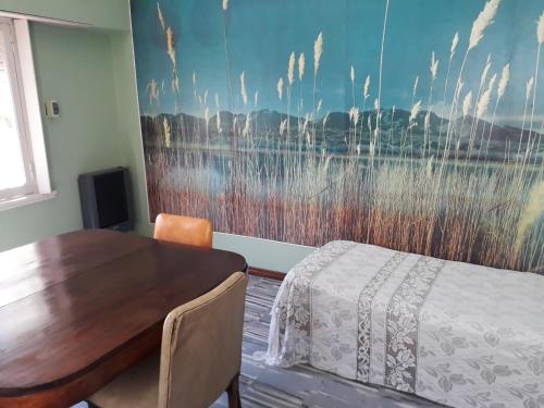 1 dormitorio con mesa de madera y una pintura en la pared en Departamento PLAYERO en Mar del Plata