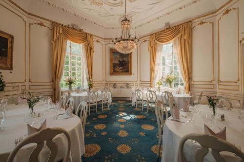 a banquet room with white tables and chairs and a chandelier at Lejondals Slott in Bro
