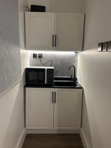 a kitchen with white cabinets and a microwave on a counter at استديو حطين البوليفارد دخول ذاتي مدخل مستقل in Riyadh