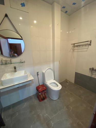 uma casa de banho com um WC, um lavatório e um espelho. em Trung Hiếu em áº¤p VÄ©nh ÃÃ´ng