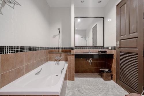 a bathroom with a large tub and a sink at Napalai Resort & Spa in Hua Hin