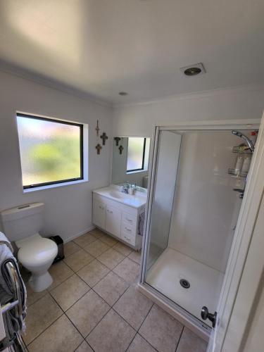 a bathroom with a shower and a toilet and a sink at The Sanctuary Papamoa Beach in Papamoa