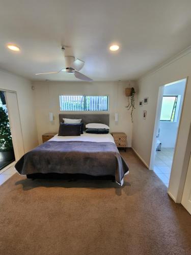 a bedroom with a large bed and a ceiling fan at The Sanctuary Papamoa Beach in Papamoa