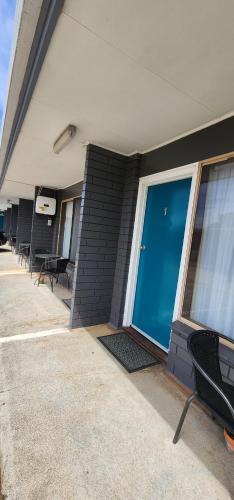 a building with a blue door and some chairs at Admella Motel in Portland