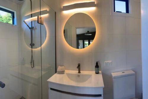 a bathroom with a sink and a mirror at Kanuka Terrace - The Little Black House in Hapuku