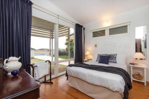 um quarto com uma cama e uma grande janela em PORT WILLUNGA DREAMING a beach front experience em Port Willunga