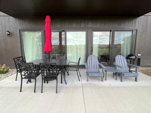 a black dining table and chairs with a red umbrella at Newly Updated Modern, Spacious, and Cozy Condo- Right on the Lake! in Lake Geneva