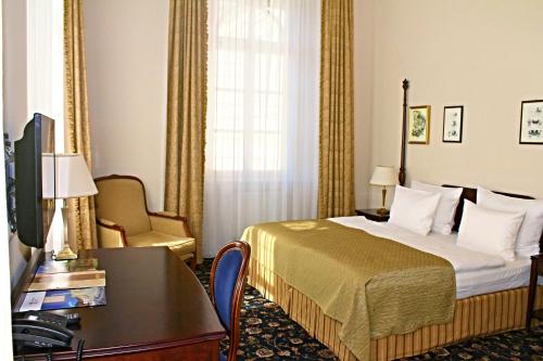 a hotel room with a bed and a desk and a television at Villa Patriot Boutique Hotel in Mariánské Lázně