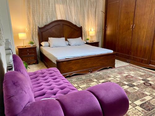 Cozy 3BR Apartment in Maadi في القاهرة: غرفة نوم مع أريكة أرجوانية وسرير
