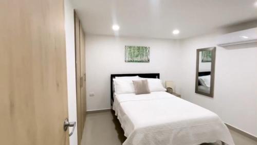 um quarto branco com uma cama e um espelho em Apartamento Amoblado de Una Habitación Doble em Ríohacha