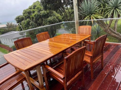 a wooden table and chairs on a deck at AHIPARA GOLDENSANDs in Ahipara