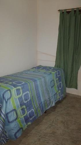 a bed in a room with a green curtain at San Miguel in Formosa