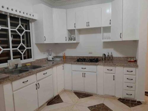a white kitchen with white cabinets and a sink at Espaciosa casa en Matancitas a 3 min de la Playa in Matancita
