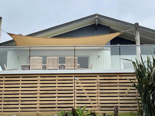 a house with a porch with chairs on it at AHIPARA GOLDENSANDs in Ahipara