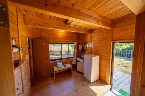 eine Küche in einer Holzhütte mit einem Kühlschrank in der Unterkunft Tsushima Miuda Pension in Tsushima