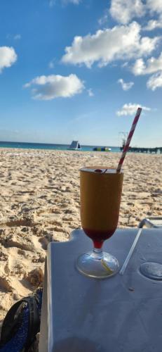 a drink sitting on a table on the beach at ShkyBlue Suites in Christ Church