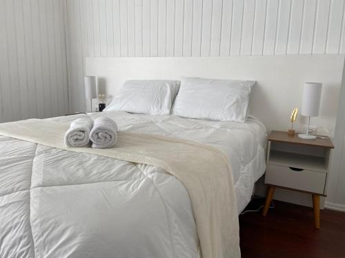 ein Schlafzimmer mit einem weißen Bett und Handtüchern darauf in der Unterkunft Blue House em Condomínio Fechado in Gramado