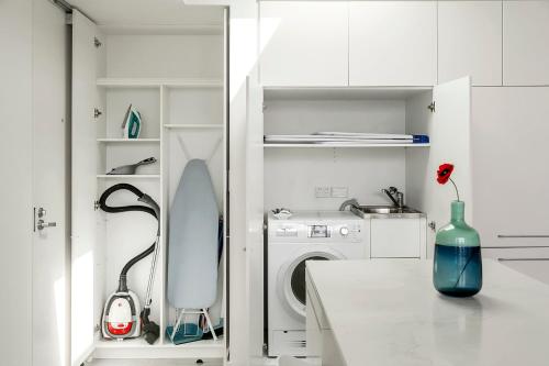 a white kitchen with a washing machine and a vase on a counter at EIGHT TWO NINE TWO VI: BONDI BEACH in Sydney