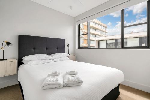 a white bedroom with a large bed with two towels on it at EIGHT TWO NINE TWO VI: BONDI BEACH in Sydney