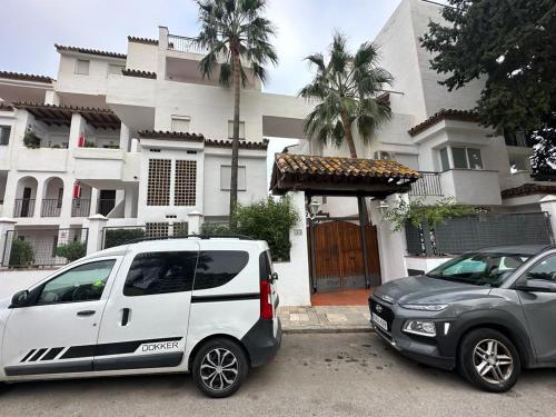two cars parked in a parking lot in front of a building at Ola Blanca Carihuela Apartamento in Torremolinos