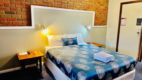 a small bedroom with a bed and a brick wall at Early Australian Motor Inn in Mildura