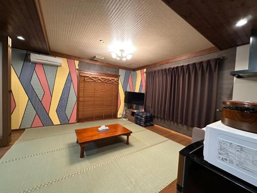 a living room with a table and a rug at Minato Oasis Numazu / 沼津観光の中心、伊豆観光の拠点に好立地！沼津港に位置し交通・飲食・コンビニ等至便です！ in Numazu