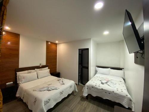 a bedroom with two beds and a flat screen tv at Hotel Yolima Real in Bogotá