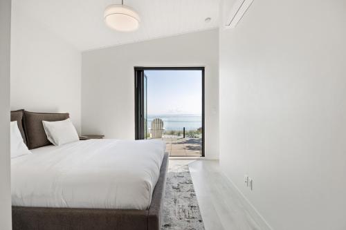 a white bedroom with a large bed and a large window at Beachfront Luxury Suite #21 at THE BEACH HOUSE in Campbell River