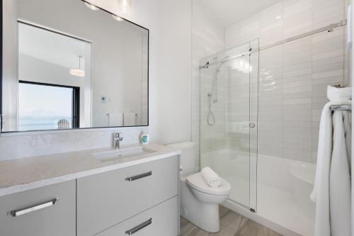 a white bathroom with a shower and a toilet at Beachfront Luxury Suite #21 at THE BEACH HOUSE in Campbell River