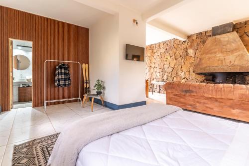 um quarto com uma cama grande e uma lareira de pedra em Lodge Pochoco Refugio de Montaña em Santiago