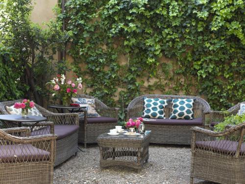 a group of wicker chairs and tables in a garden at Al Palazzo del Marchese di Camugliano Residenza d'Epoca in Florence
