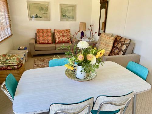 ein Wohnzimmer mit einem Tisch und einer Blumenvase darauf in der Unterkunft Sisters Beach House in Sisters Beach