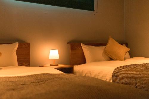 two beds in a room with a lamp on a table at なでしこ町家 in Fukuoka