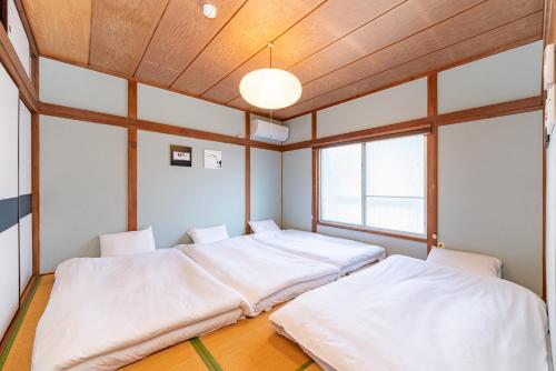 two beds in a room with wooden ceilings at GuestHouse　YOU&I平和島 in Tokyo