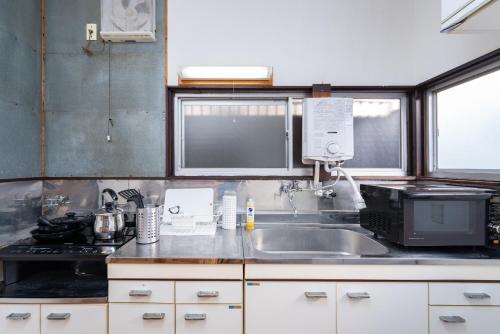 una cucina con lavandino e forno a microonde di GuestHouse　YOU&I平和島 a Tokyo