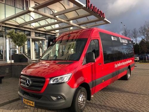 een rood en zwart busje geparkeerd voor een gebouw bij Ramada by Wyndham Amsterdam Airport Schiphol in Badhoevedorp