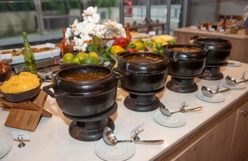 a buffet line with bowls of food and spoons at Ribalta Hotel Barra da Tijuca by Atlantica in Rio de Janeiro