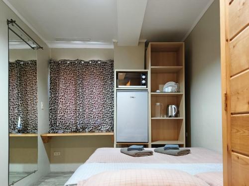 Zimmer mit einem Bett, einem Kühlschrank und Regalen in der Unterkunft Misty Hills in Baguio City