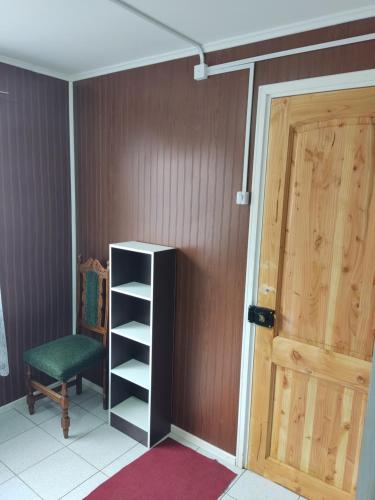 um quarto com uma porta, uma cadeira e uma prateleira em Mini cabaña nueva independiente em Temuco