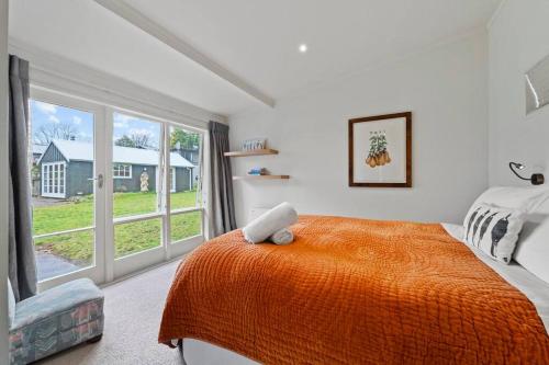 a bedroom with an orange bed and a large window at Otupai Cottage in Taupo