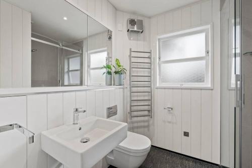 Baño blanco con lavabo y aseo en Otupai Cottage, en Taupo