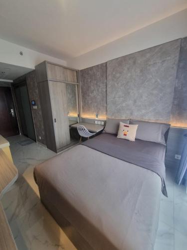 a bedroom with a large bed and a chair at Mashley Room Prestige Apartment SKY HOUSE BSD in Cilandak