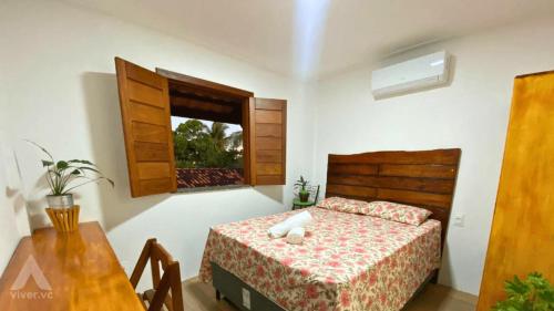 a bedroom with a bed and a table and a window at Viva Guaibim: Casa de Praia com Piscina e Churrasqueira in Guaibim