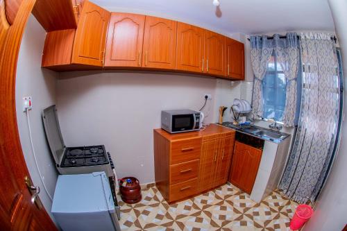 a small kitchen with wooden cabinets and a microwave at A&B Cozy Apartments Kitale in Kitale
