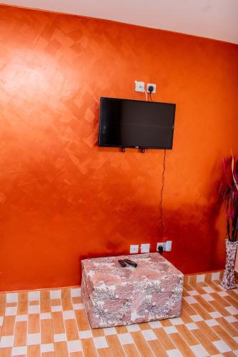 an orange wall with a flat screen tv on a wall at A&B Cozy Apartments Kitale in Kitale