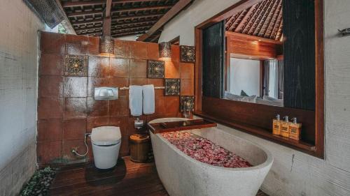a bathroom with a large tub and a mirror at Black Penny Villas Ubud in Ubud