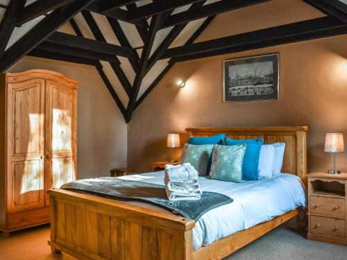 a bedroom with a large wooden bed with blue pillows at Larpool Mews in Whitby