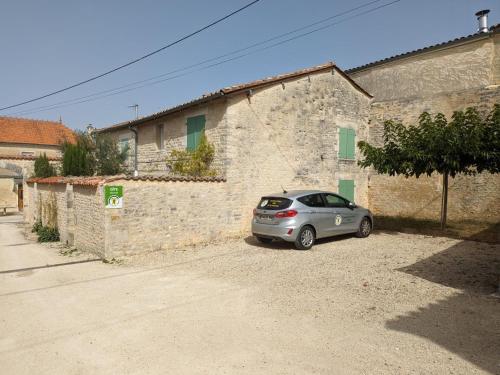a silver car parked in front of a brick building at Charmante maison en pierre avec cour privée, équipements bébé, vélos, proche de la Charente - FR-1-653-91 in Coulonges