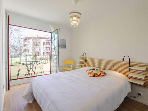 une chambre avec un grand lit blanc et un balcon dans l'établissement Bel appartement rénové, calme, proche centre et plage, balcon, 2 chambres, commerces à 150m - FR-1-4-685, à Saint-Jean-de-Luz