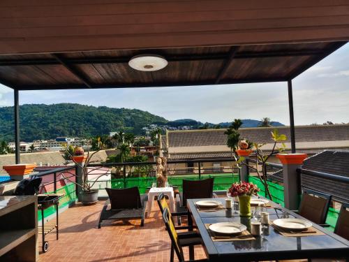 a patio with tables and chairs on a balcony at Kata Lina guesthouse in Kata Beach
